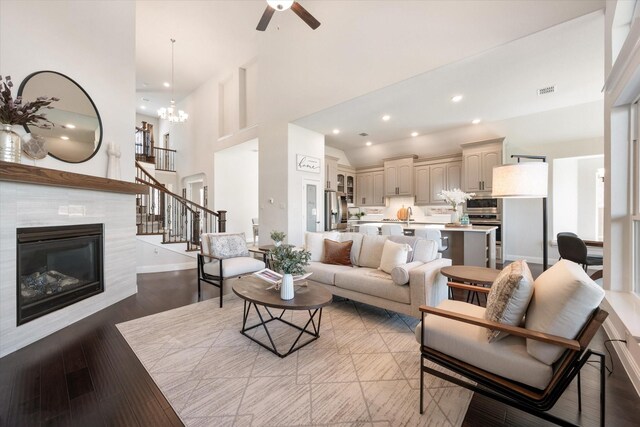 living room featuring hardwood / wood-style floors, a high ceiling, a tile fireplace, and a notable chandelier