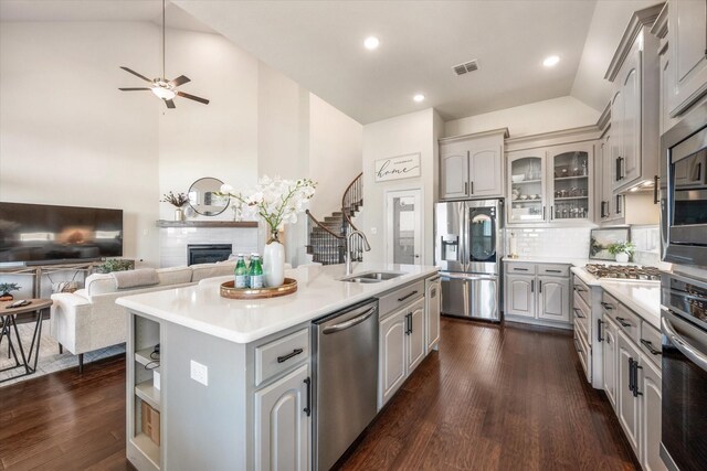 kitchen featuring a center island with sink, stainless steel appliances, gray cabinetry, decorative light fixtures, and sink