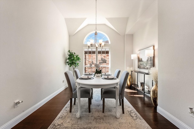 dining room with vaulted ceiling, dark wood-type flooring, and an inviting chandelier