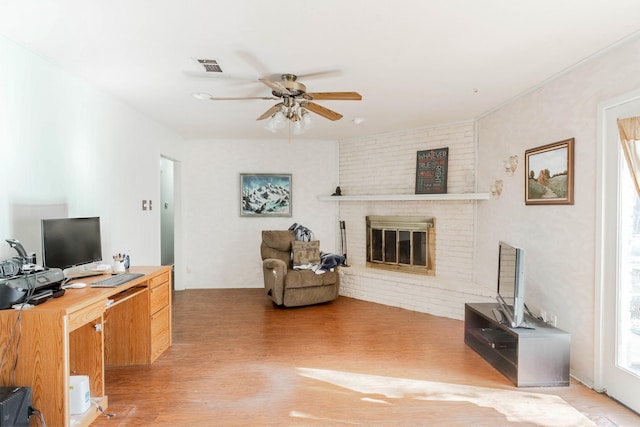 living room featuring ceiling fan, a fireplace, and light hardwood / wood-style flooring