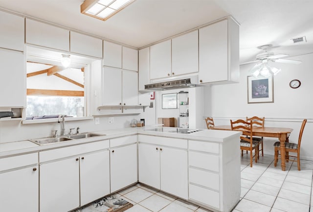 kitchen with black electric stovetop, white cabinets, and sink