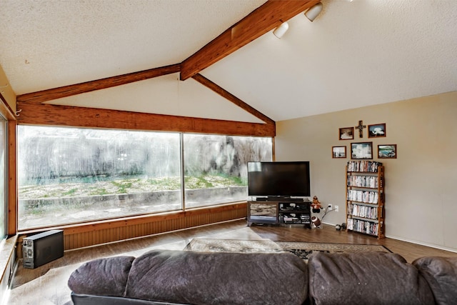 living room with a textured ceiling, a healthy amount of sunlight, and vaulted ceiling with beams