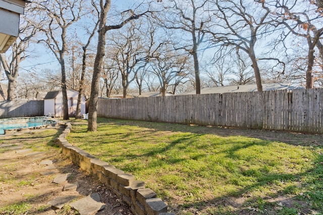 view of yard with a fenced in pool and a storage shed