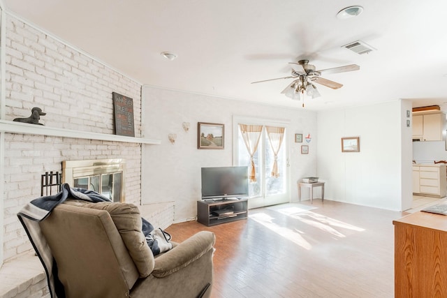 living room with ceiling fan, a fireplace, and hardwood / wood-style flooring