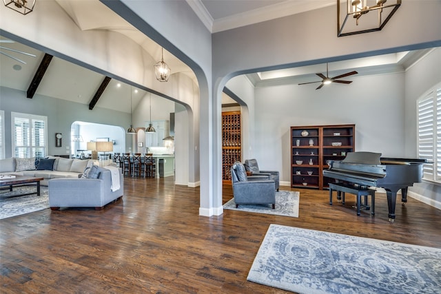 living room with dark wood-type flooring, a wealth of natural light, and ceiling fan with notable chandelier