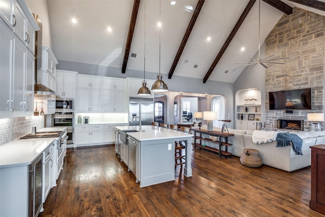 kitchen featuring decorative light fixtures, backsplash, white cabinets, and a kitchen island with sink