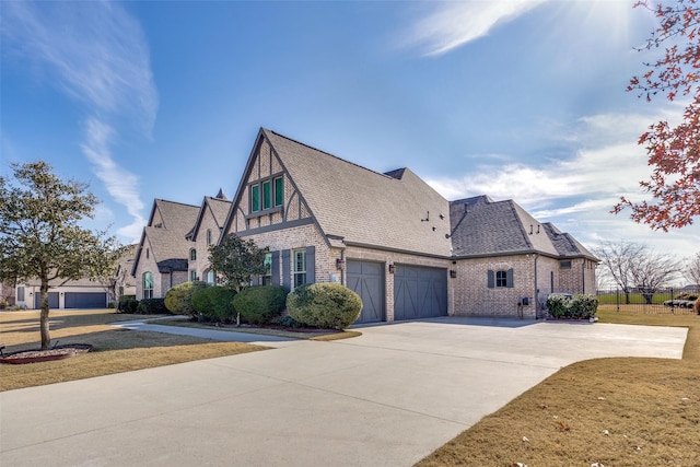 view of home's exterior with a lawn, roof with shingles, concrete driveway, a garage, and brick siding