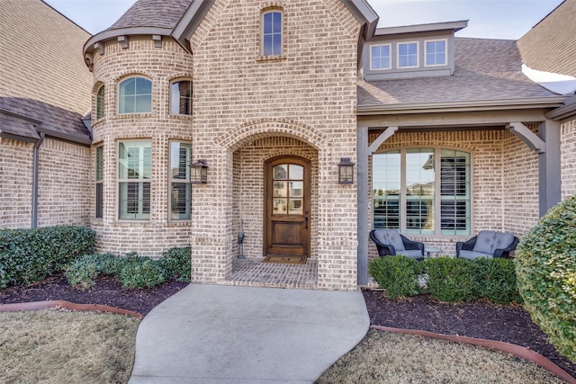 property entrance featuring brick siding and roof with shingles