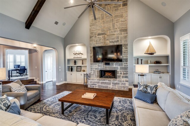 living room with ceiling fan with notable chandelier, built in shelves, a stone fireplace, dark hardwood / wood-style floors, and high vaulted ceiling