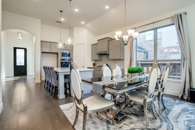 dining area with dark hardwood / wood-style flooring, lofted ceiling, and a notable chandelier