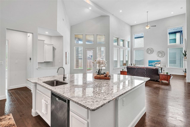 kitchen featuring a center island with sink, stainless steel dishwasher, open floor plan, white cabinetry, and a sink