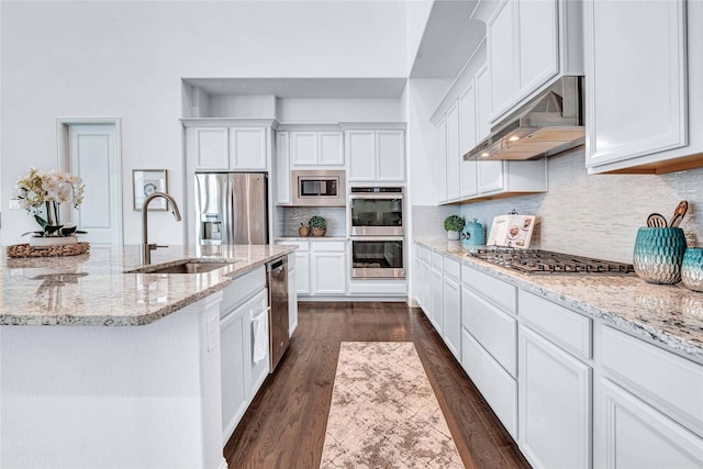 kitchen with decorative backsplash, stainless steel appliances, under cabinet range hood, white cabinetry, and a sink