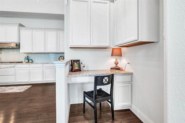 kitchen featuring baseboards, dark wood finished floors, decorative backsplash, built in desk, and white cabinetry