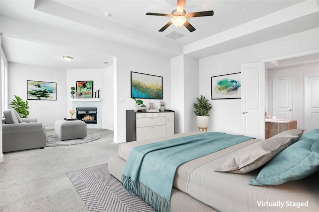 carpeted bedroom featuring baseboards, visible vents, ensuite bath, ceiling fan, and a stone fireplace