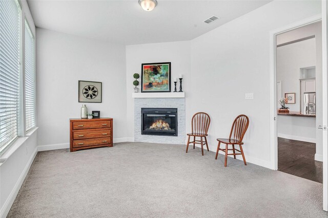 living area featuring carpet floors, a glass covered fireplace, visible vents, and baseboards