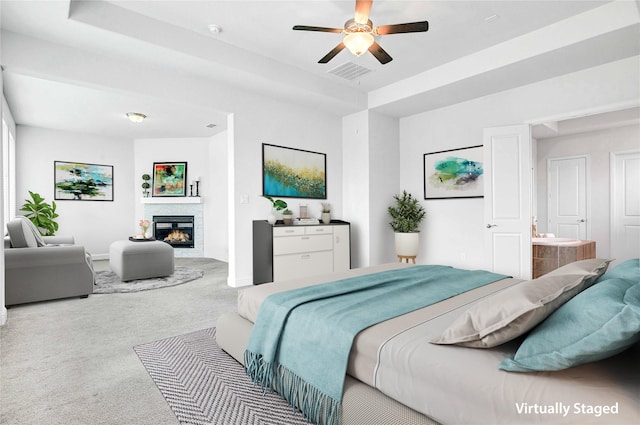 carpeted bedroom with a stone fireplace, a ceiling fan, ensuite bath, and baseboards