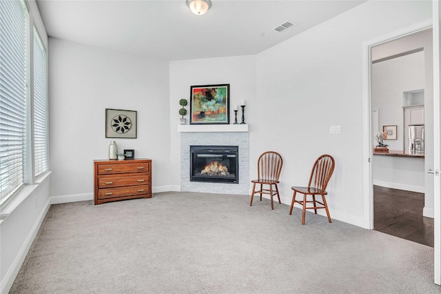 sitting room with carpet floors, a glass covered fireplace, and baseboards