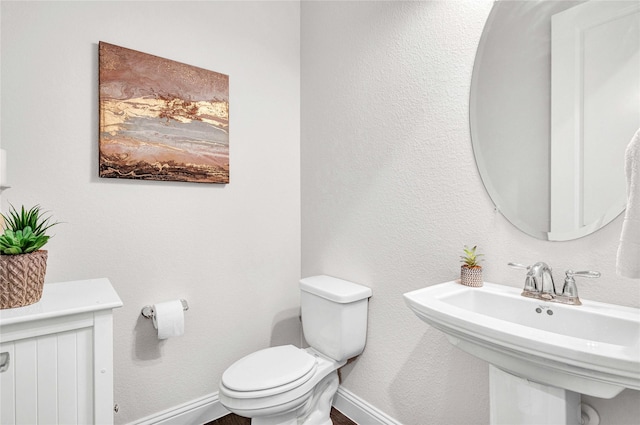 bathroom with toilet, baseboards, and a sink