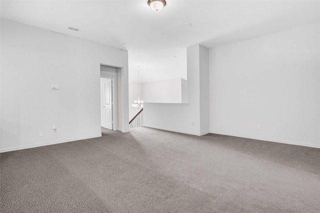 unfurnished room featuring a notable chandelier, carpet, visible vents, and baseboards