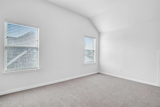 carpeted spare room with baseboards and lofted ceiling