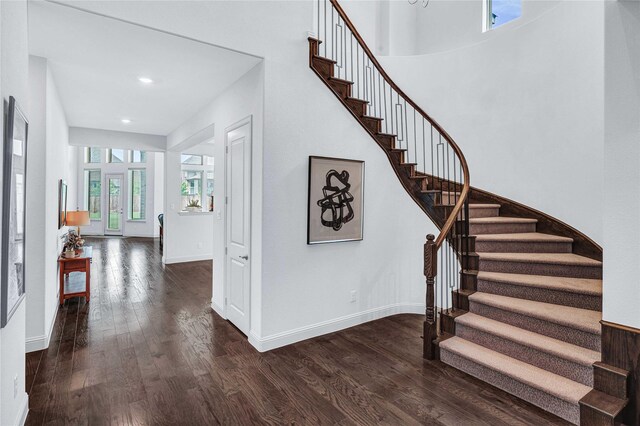 stairs with a high ceiling, recessed lighting, wood finished floors, and baseboards