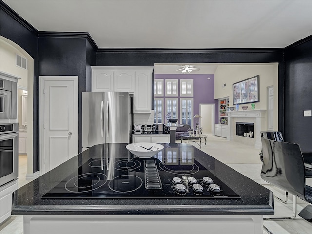 kitchen with ceiling fan, appliances with stainless steel finishes, backsplash, dark stone counters, and white cabinets