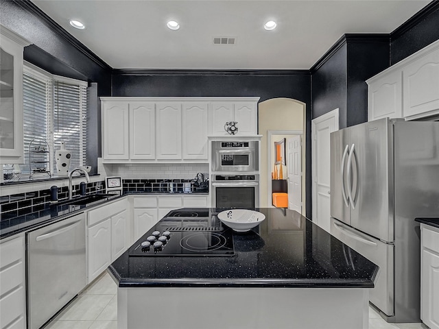 kitchen with a kitchen island, sink, ornamental molding, stainless steel appliances, and white cabinets