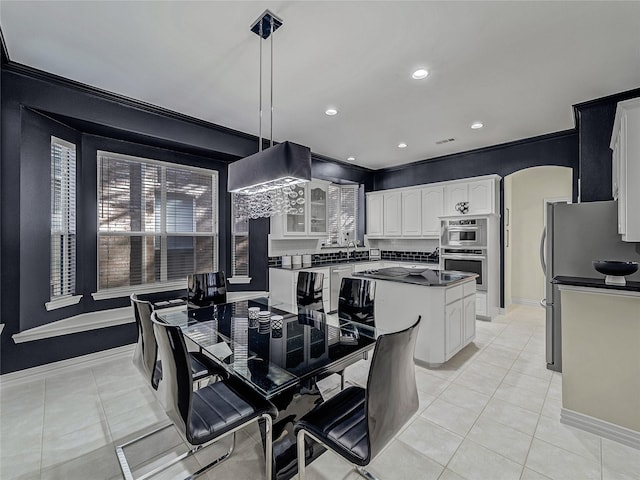 kitchen with white cabinetry, appliances with stainless steel finishes, decorative light fixtures, light tile patterned flooring, and a center island