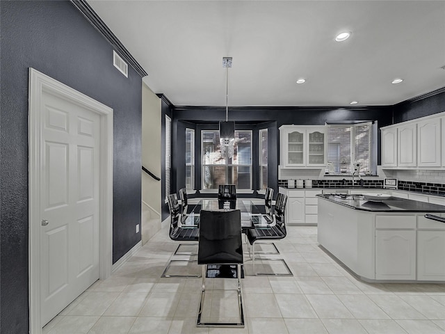 kitchen featuring light tile patterned floors, white cabinetry, backsplash, a kitchen breakfast bar, and pendant lighting