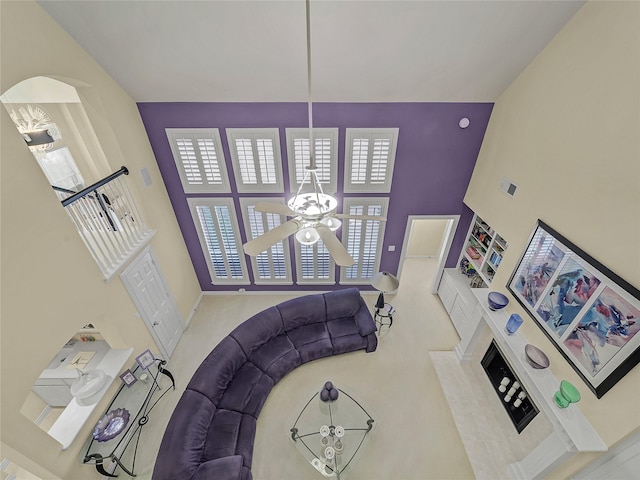 foyer featuring a premium fireplace, ceiling fan, a towering ceiling, and carpet floors