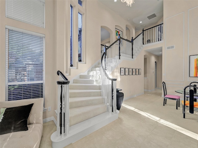 stairs with an inviting chandelier, tile patterned floors, and a high ceiling