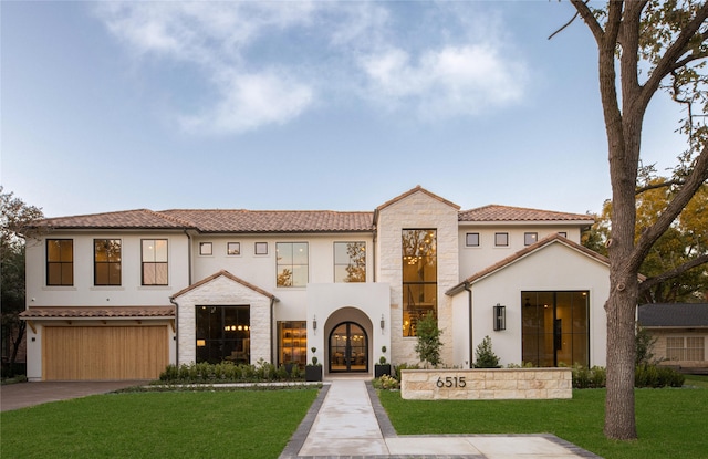 mediterranean / spanish-style home featuring a front yard, a garage, and french doors