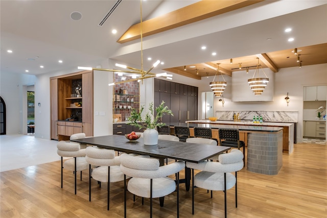 dining area with a chandelier, light hardwood / wood-style floors, and beam ceiling