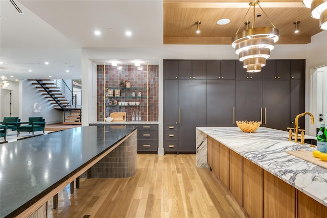 kitchen with light stone counters, wooden ceiling, an inviting chandelier, and light wood-type flooring