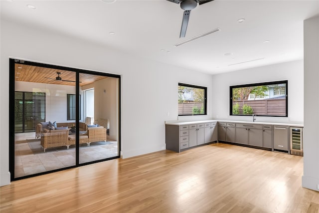 spare room featuring ceiling fan, beverage cooler, and light hardwood / wood-style flooring