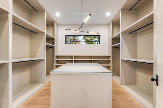 walk in closet featuring light wood-type flooring and a notable chandelier