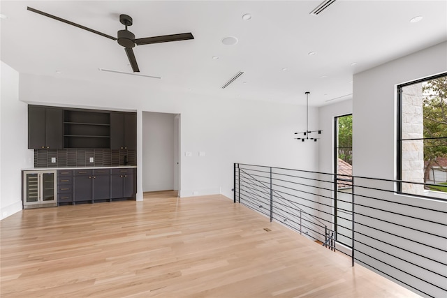 interior space featuring light wood-type flooring and ceiling fan with notable chandelier