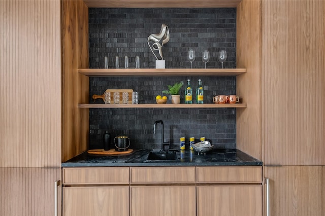 bar featuring tasteful backsplash, dark stone counters, and sink