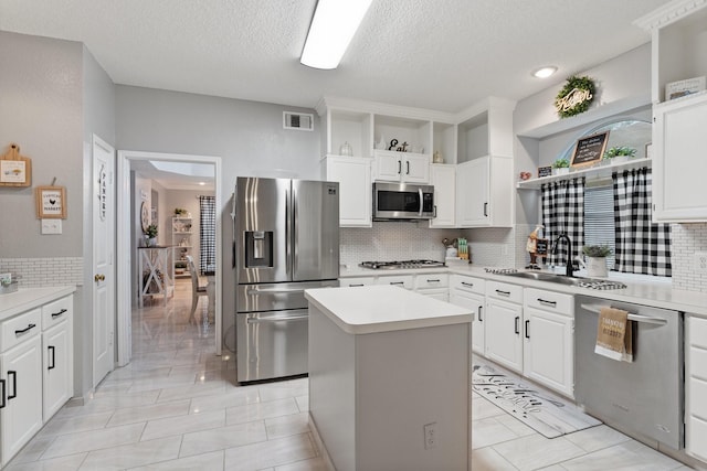 kitchen featuring white cabinetry, appliances with stainless steel finishes, tasteful backsplash, and a kitchen island