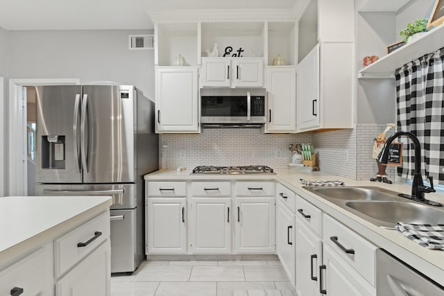 kitchen featuring appliances with stainless steel finishes, white cabinetry, decorative backsplash, sink, and light tile patterned flooring