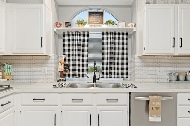 kitchen featuring stainless steel dishwasher, white cabinets, decorative backsplash, and sink