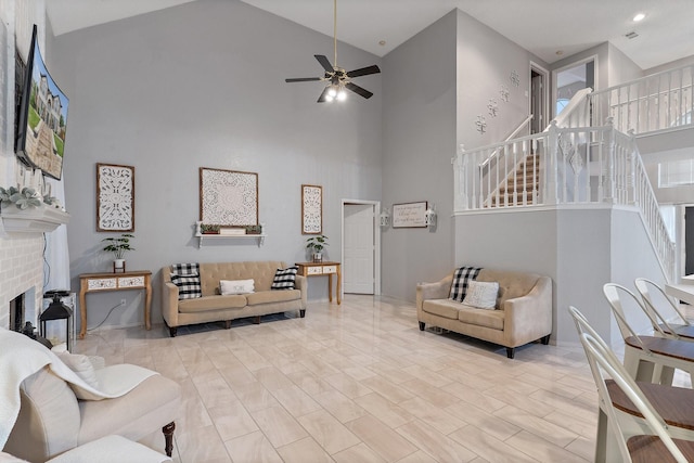 living room featuring light wood-type flooring, ceiling fan, a fireplace, and high vaulted ceiling