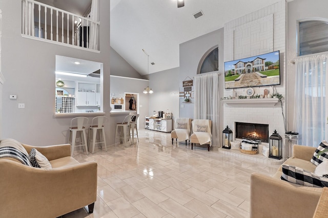 living room featuring high vaulted ceiling and a brick fireplace