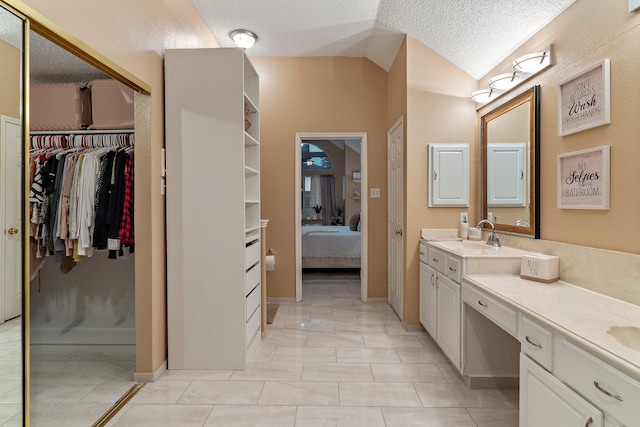 bathroom with a textured ceiling, vanity, and lofted ceiling