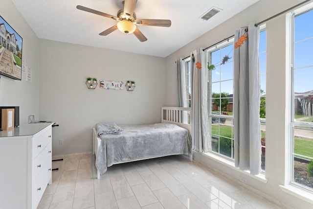 tiled bedroom featuring ceiling fan and multiple windows