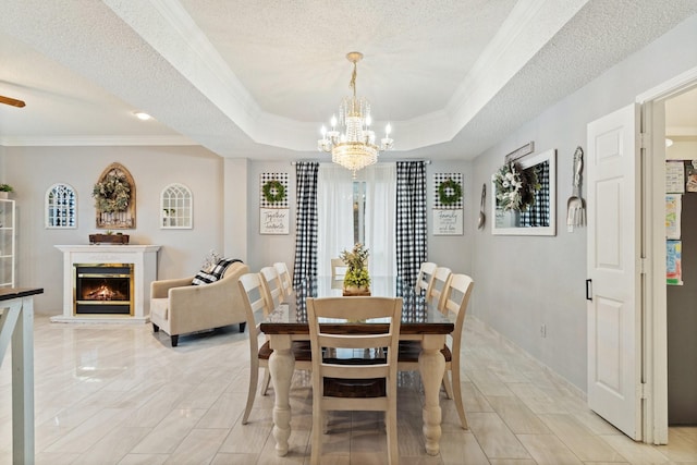 dining space with a textured ceiling, a tray ceiling, ornamental molding, and a notable chandelier