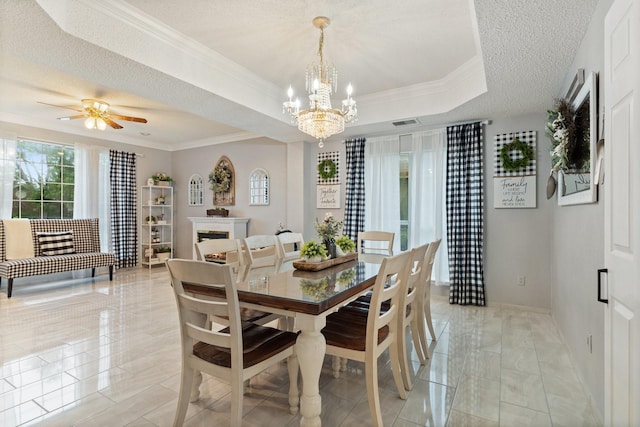 dining space featuring a tray ceiling, ceiling fan with notable chandelier, a textured ceiling, and ornamental molding