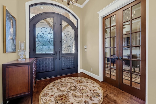 entrance foyer with dark hardwood / wood-style flooring, crown molding, french doors, and an inviting chandelier