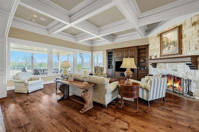 living room featuring dark hardwood / wood-style floors, beamed ceiling, crown molding, coffered ceiling, and a stone fireplace