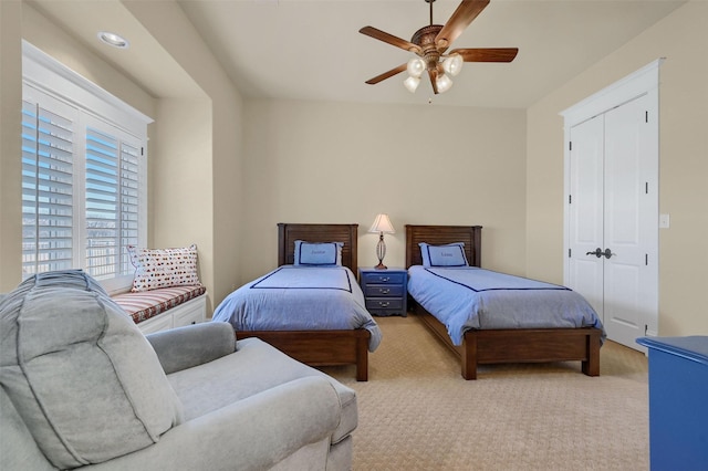 bedroom with ceiling fan, light colored carpet, and a closet